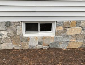 Stone veneer covers the concrete foundation on the exterior of the home